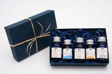 Load image into Gallery viewer, Set of five small bottles of hand oil in a decorative box with a matching navy blue box.